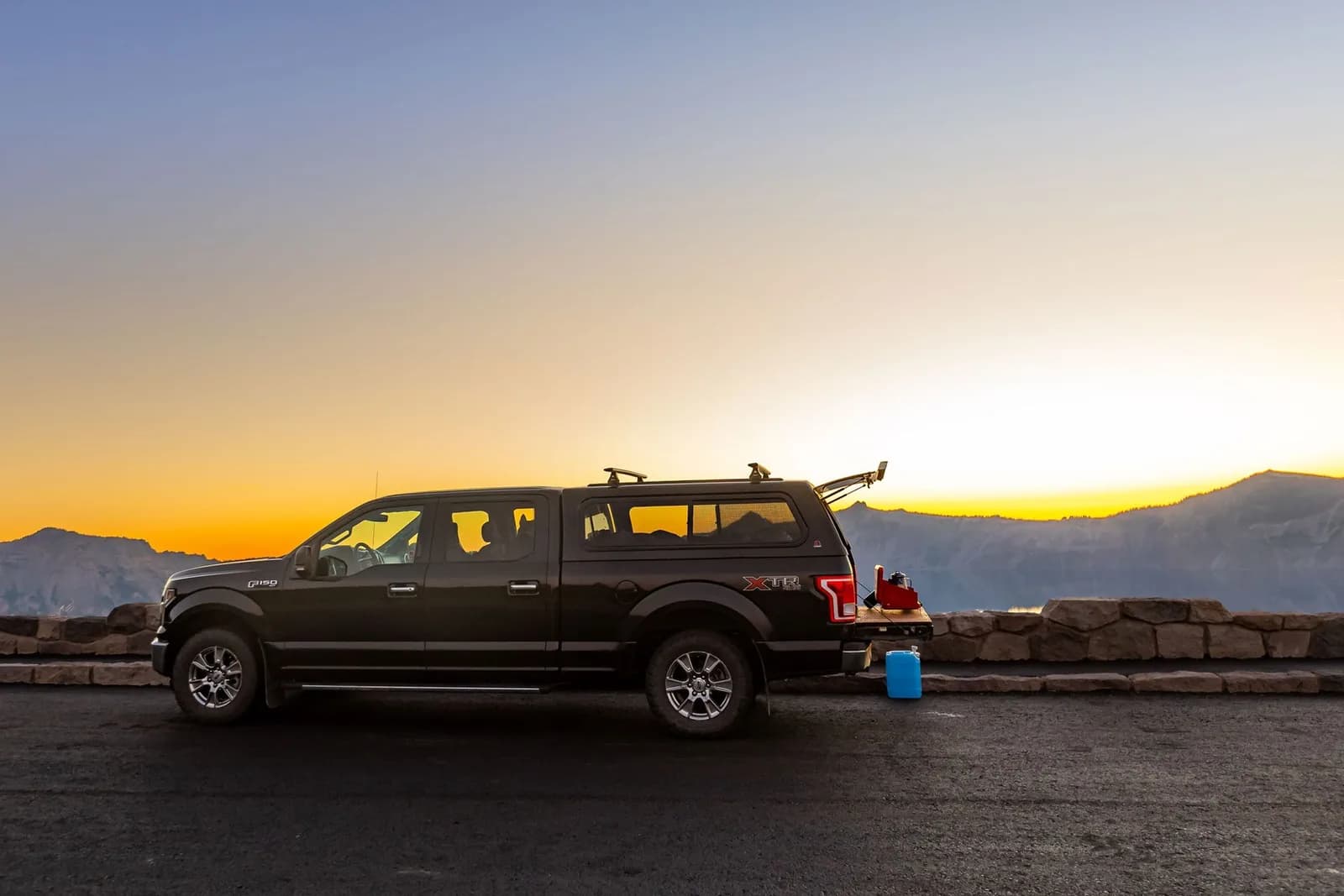 Ford F-150 with a truck cap parked at a mountain overlook at sunset