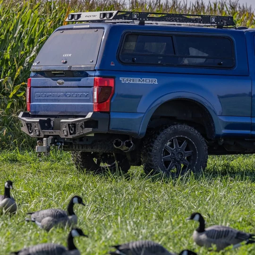 Blue Ford Super Duty fitted with a truck cap and roof rack