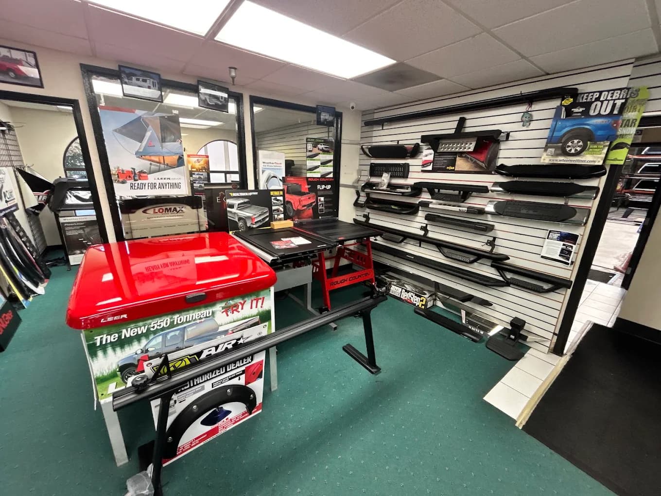 Wall of running boards and nerf bars beside a red LEER 550 tonneau display