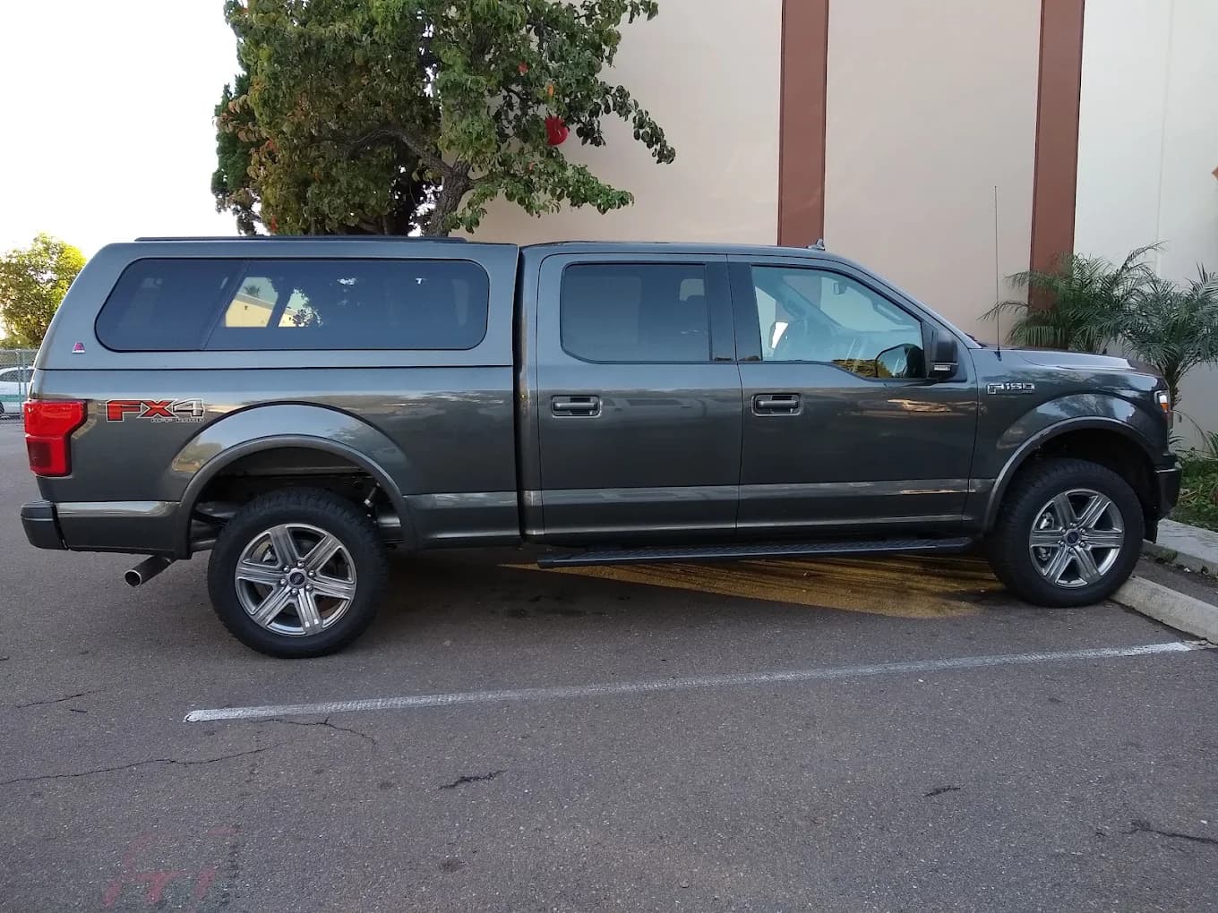 Grey Ford F-150 FX4 with a color-matched cap and running boards, full side profile