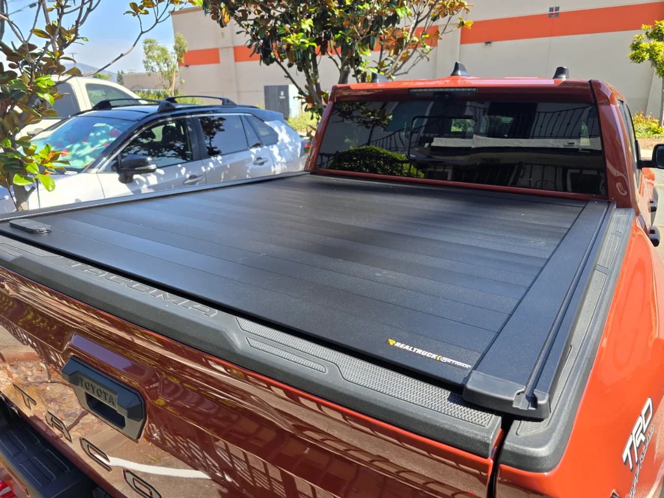 Retractable hard tonneau cover fitted to an orange Toyota Tacoma TRD