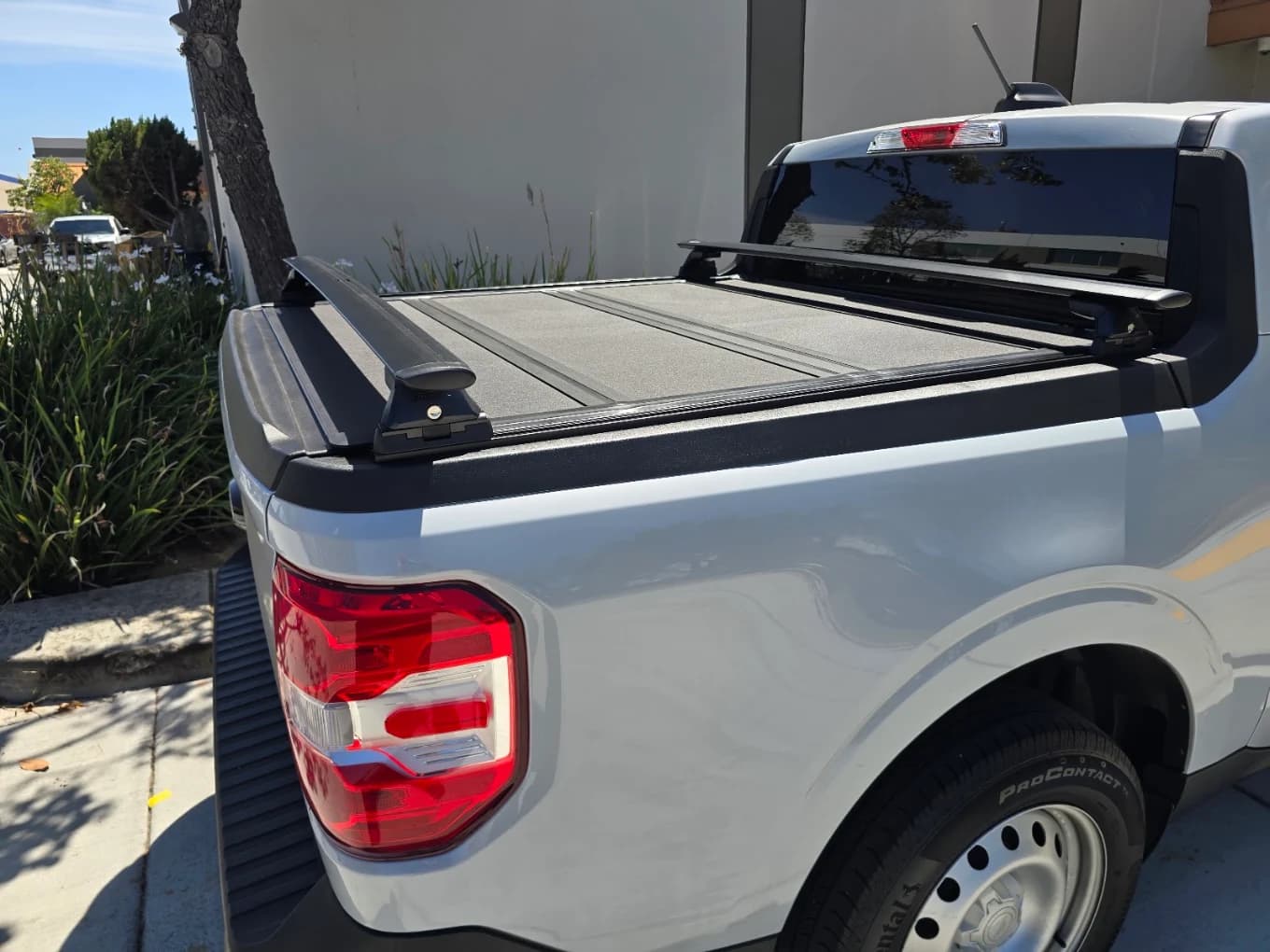 Folding hard tonneau cover and crossbars fitted to a white Ford Maverick