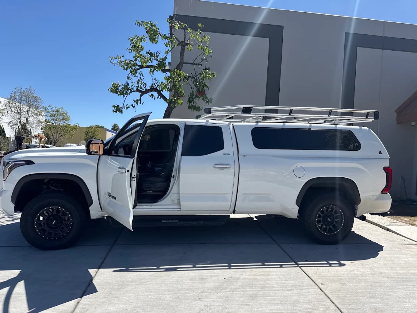 White Toyota Tundra with a tall commercial cap and a full-length aluminium rack above it